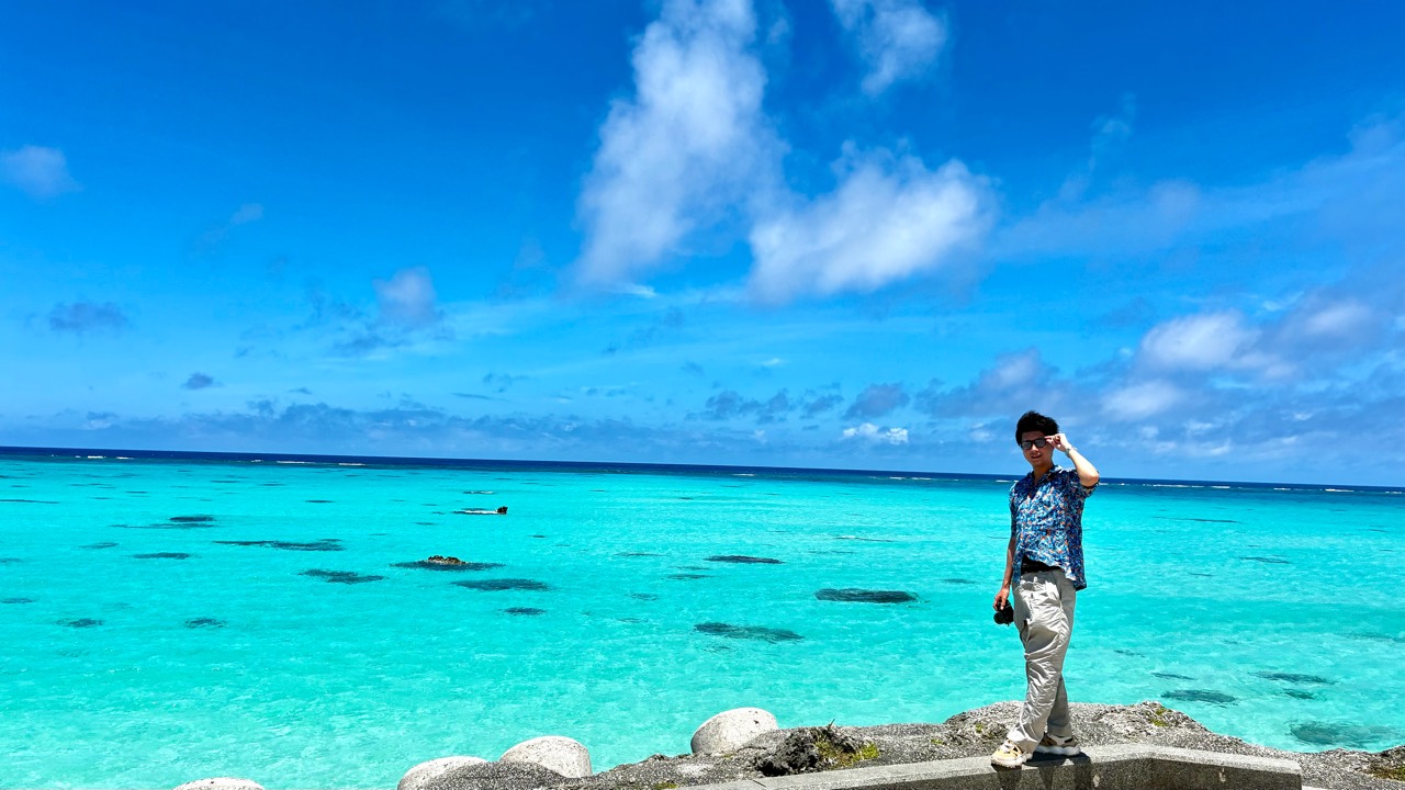 青い海を背景にカメラを持つ林幸弥